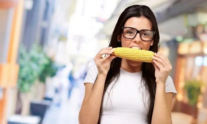 Молодая девушка ест кукуруза